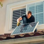Solar technician installing a photovoltaic panel on a rooftop, promoting renewable energy.